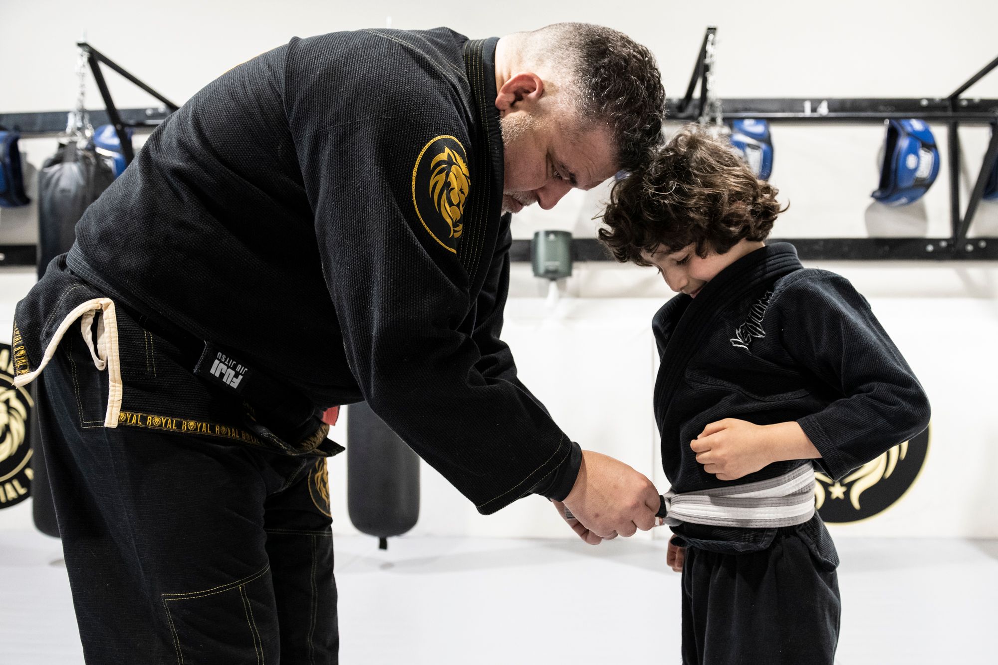 instructor tying new belt on kids jiu jitsu student at Royal Mixed Martial Arts