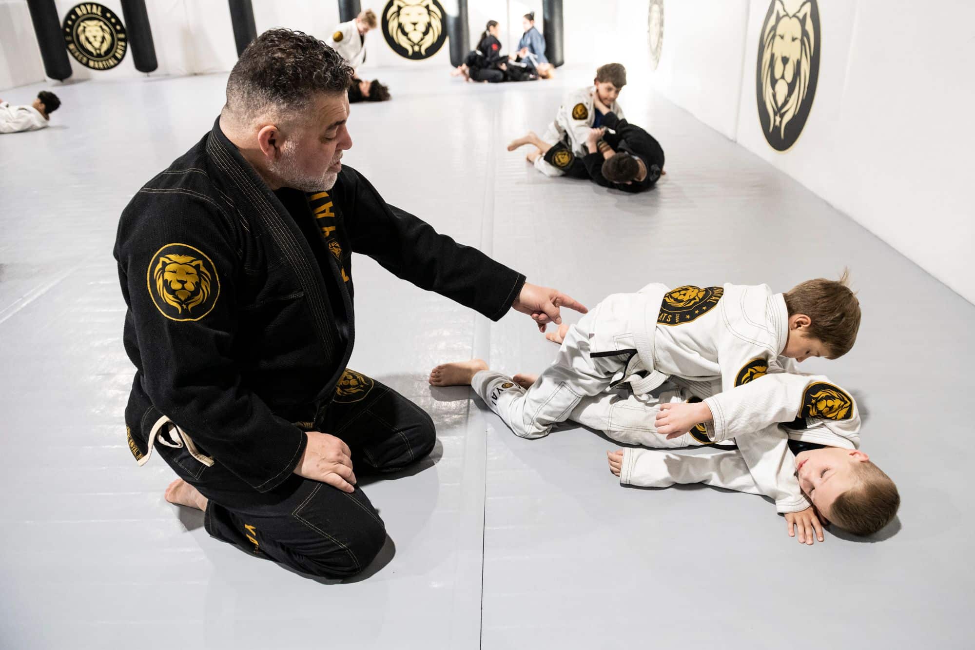 two young students at Royal Mixed Martial Arts getting taught by instructor at kids jiu jitsu class