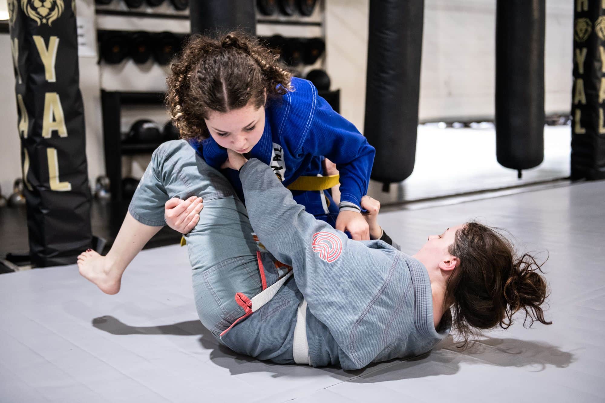 two female Royal Mixed Martial Arts students sparring for jiu jitsu class